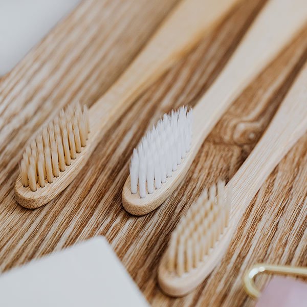 Tre spazzolini in bamboo appoggiati su un piano di legno, linea Etico proposta a Perugia