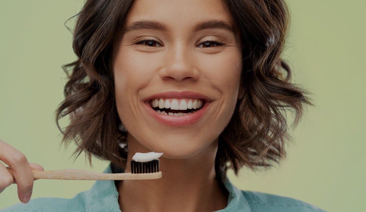 Donna sorridente con uno spazzolino in bamboo della linea Etico